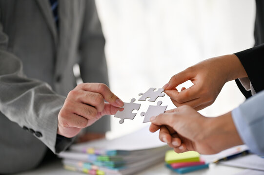 Close-up image of diverse businesspeople holding a piece of jigsaw puzzle in the meeting