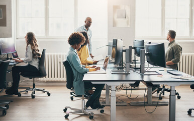 Group of diverse businesspeople sitting at office desks and working on computers