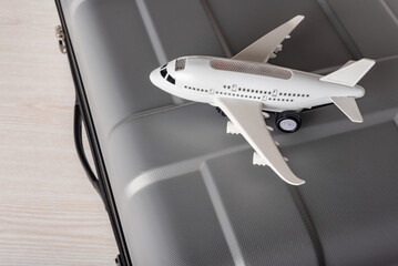Airplane model and suitcase on wooden background, recreation traveling concept