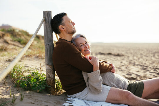 Man embracing woman sitting at beach