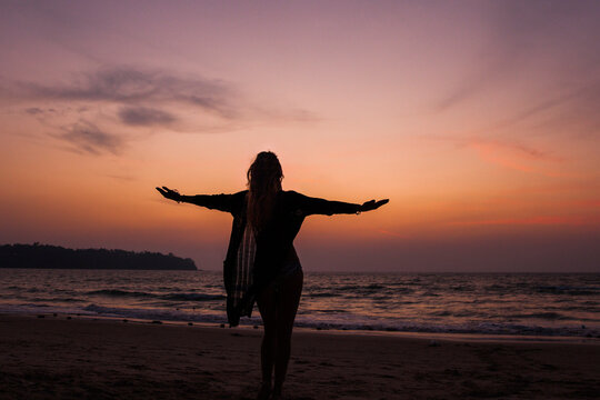 Silhouette of woman standing with arms outstretched standing at beach
