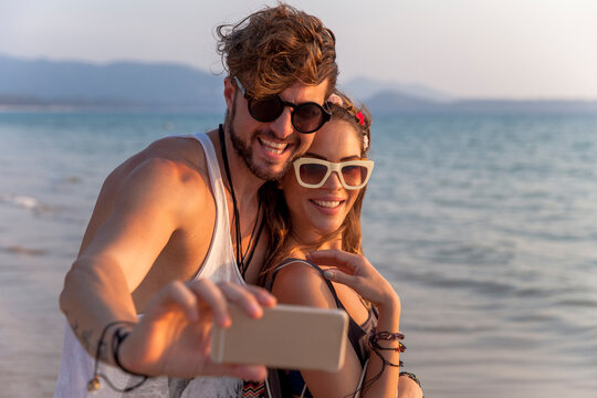 Man taking selfie through mobile phone with girlfriend at beach