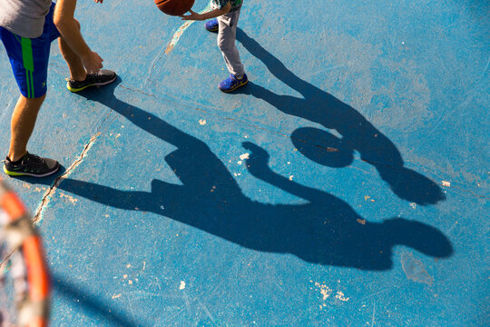 Man playing basketball with son at sports court