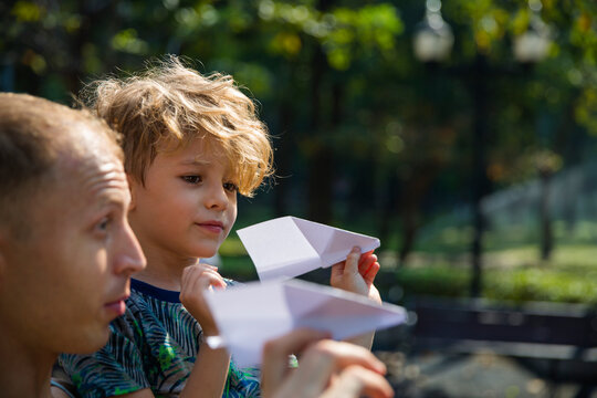 Son And Father Playing With Paper Airplanes