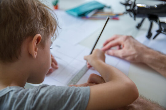 Father helping son drawing on paper at desk