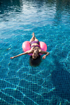 Carefree woman enjoying vacation in swimming pool at sunny day