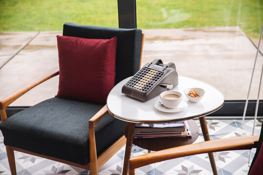 Coffee and cookies with old adding machine on table by chair