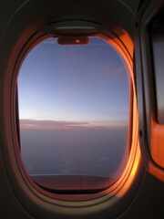 View from the airplane window to the sea and blue sky at sunset