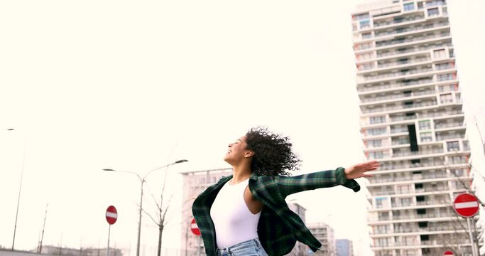 Carefree woman dancig in the street with arms outstretched