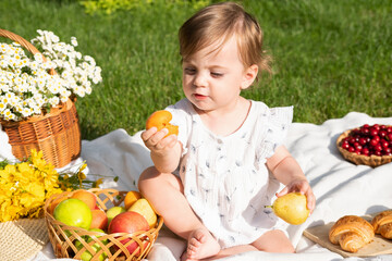 Cute little baby eating organic fruits on picnic in the summer park