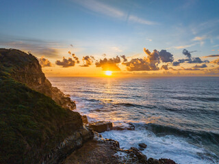 Sunrise and clouds over the ocean and rock platform