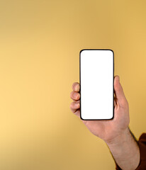 Cropped hand of businessman showing smart phone with blank white screen against beige background. Young male entrepreneur holding cellphone with empty free space for advertisement