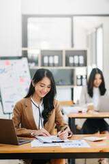 Young attractive Asian female office worker business suits smiling at camera in modern office .