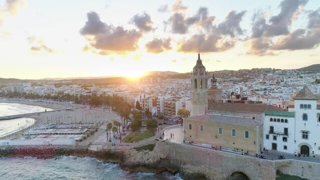 Aerial view of Sitges coastline at sunset. Sant Bartomeu i Santa Tecla church. Famous beaches near Barcelona.