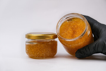 A hand in a black glove holds an open jar of pike caviar on a white background. Healthy food...