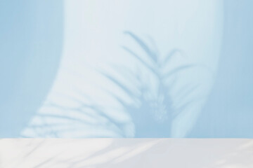 Abstract light blue background. The shadow of tropical plant leaves on a paper .