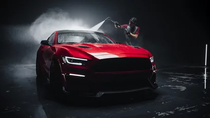 Fototapeten Adult Car Washer in Uniform Washing a Red Performance Car with a High Pressure Cleaner. Cleaning Technician Working on a Stylish American Car in a Dark Room. Commercial Studio Footage for Advertising © Gorodenkoff