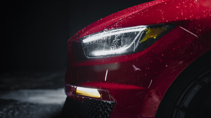 Modern Red Performance Vehicle with LED Headlights is Being Cleaned at a Dealership Car Wash. Close...