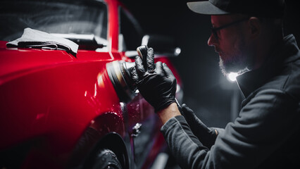 Car Ad Style Photo of a Professional Car Detailer Using an Electric-Powered Polishing Machine to Work on a Fender of a Beautiful Red Sportscar After Washing and Detailing the Vehicle