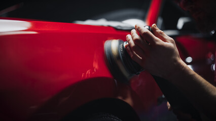 Car Ad Style Photo of a Professional Car Detailer Using an Electric-Powered Polishing Machine to...