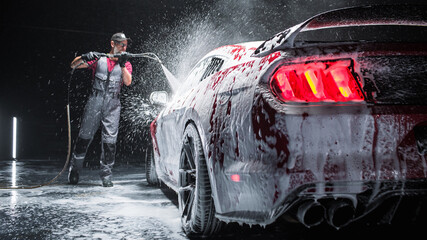 Automotive Detailer Washing Away Smart Soap and Foam with a Water High Pressure Washer. Close Up of...