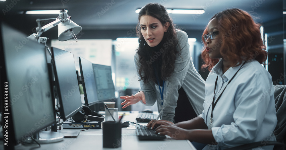 Fototapete two diverse colleagues having a conversation while busy working on a team project. african female de