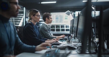 Focused Young Multiethnic Female Software Developer Working on Computer Together with Two Creative...