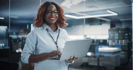 Portrait of a Black Diverse Female Wearing Glasses, Using Laptop Computer, Looking at Camera and...