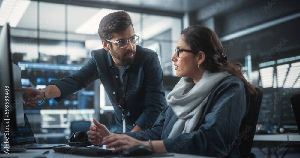 Poster Two Diverse Multiethnic Indian Colleagues Having a Conversation While Busy Working on a Software Development Project. Female Engneer Talking with a Project Manager. Teamwork in Technology Laboratory