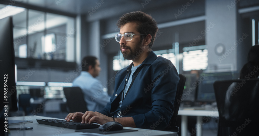 Fototapete Portrait of an Indian Engineer Working on Desktop Computer in a Technological Office Environment. South Asian Software Developer Researching New Ideas to Problem Solve a Technical Assignment