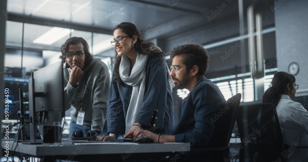 Poster Group of Three Young Indian Software Engineers Use Computer to Discuss a Technological Project in Modern Industrial Office. Group of Male and Female Scientists Work in Research and Development Center