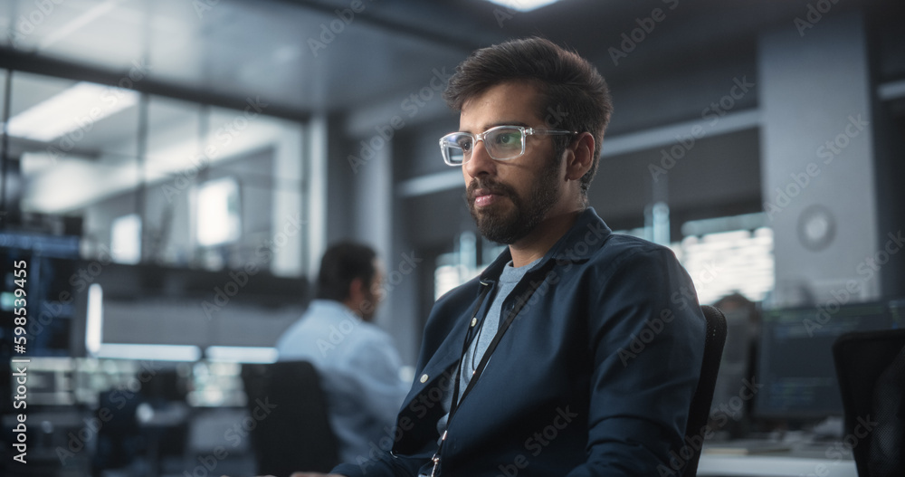 Leinwandbilder Handsome Indian Software Developer Working on Computer in a Technological Laboratory Environment. Young Man is Thoughtful at His Workplace, Drafting Research Ideas for an AI Development Blockchain