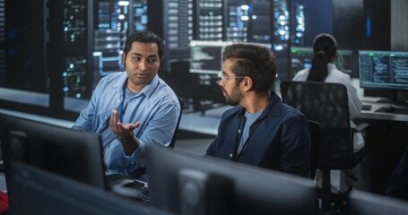 Young Colleagues Working on Computers and Having a Conversation at a Workplace. Two Indian Software Developers Discussing a Solution for Their Collaborative Artificial Intelligence Project
