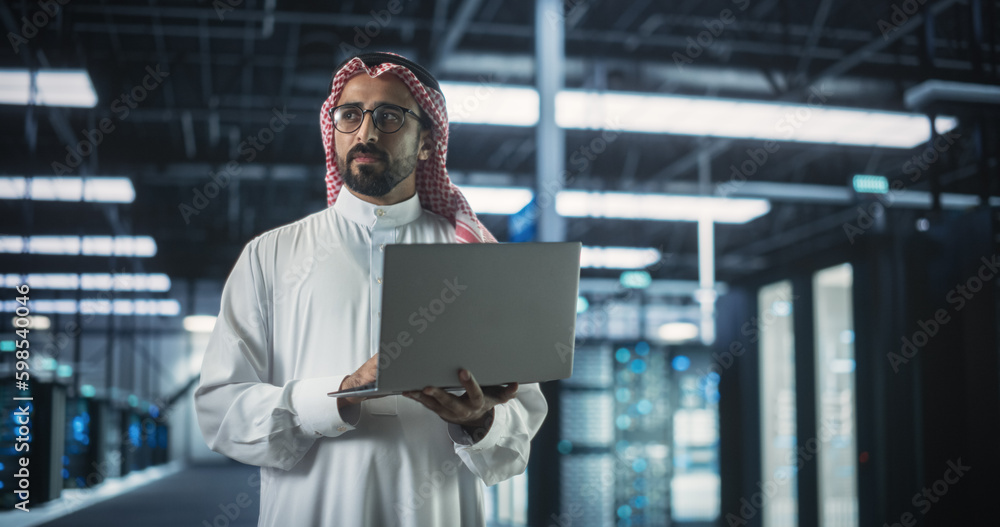Poster Muslim Data Center IT Engineer Standing in a Room with Operational Server Racks. Cloud Computing Architect Uses Laptop Computer for Servicing the System in Cyber Security and Data Protection Facility