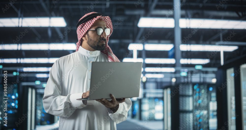 Leinwandbilder portrait of a middle eastern it system engineer wearing traditional white robe, using laptop compute