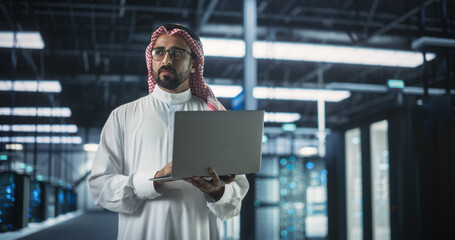 Muslim Data Center IT Engineer Standing in a Room with Operational Server Racks. Cloud Computing...