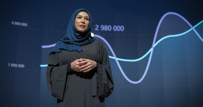 Female Business Executive Introduces New Software Product on Stage at a Conference. Arab Expert Does Motivational Talk. Speaker Having a Lecture about Science, Technology, Development, Leadership - Powered by Adobe