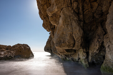 Detail of moving water with silk effect between the cliffs of the quiet Spanish beach