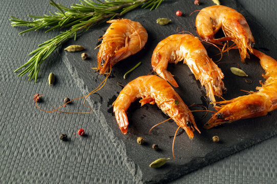 Caridea or boiled shrimps with rosemary on a gray table. The idea of delicious dietary seafood for lunch or dinner