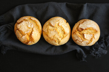 Three buns in a row on a black board with a dark cloth. Selective focus with natural light.