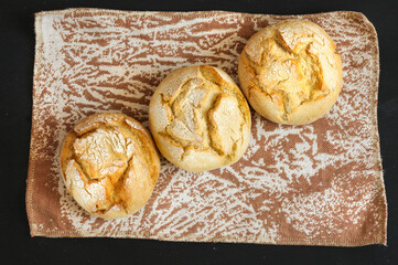 Fresh buns lie diagonally on brown vintage fabric, top view, selective focus, daylight