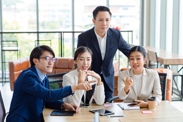 Group of successful professional asian businessman and businesswoman in formal suit sitting at desk consulting planning work in company