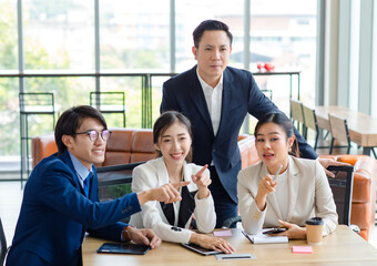 Group of successful professional asian businessman and businesswoman in formal suit sitting at desk consulting planning work in company