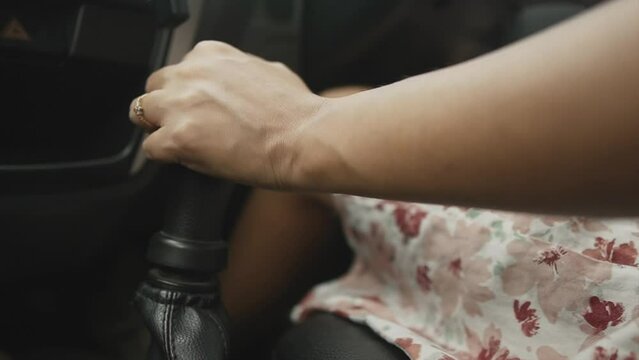 A modern girl's hand with a wedding ring on her finger. A married girl manually controls a manual transmission, shifts gears in a car. A close-up of a woman's hand.