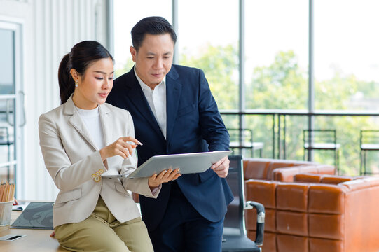 Asian Professional Successful Female Businesswoman Secretary Employee Showing Information Strategy Data Via Laptop Notebook Computer To Male Businessman Manager In Formal Business Suit In Living Room