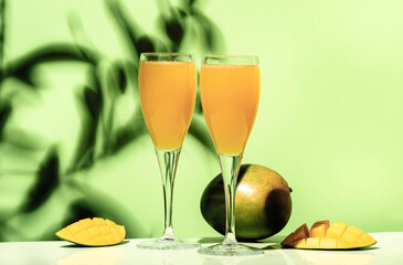 Mango bellini alcoholic cocktail with prosecco or sparkling wine, mango puree, syrup and ice. Light green background, hard light, shadow pattern