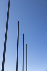 a group of empty metal flagpoles against a blue sky background