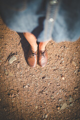 Close up image of a pretty woman with muscular legs walking on a dirt road wearing handmade leather shoes.