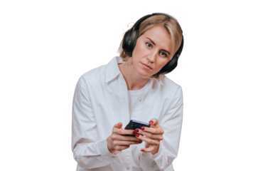 Upset blonde American young woman in white shirt using headphones and phone against transparent background, enjoys sad music, frustrated after failure. Tired caucasian girl unhappy, receives bad news.