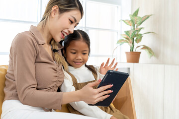 Young mother and little daughter use tablet in living room